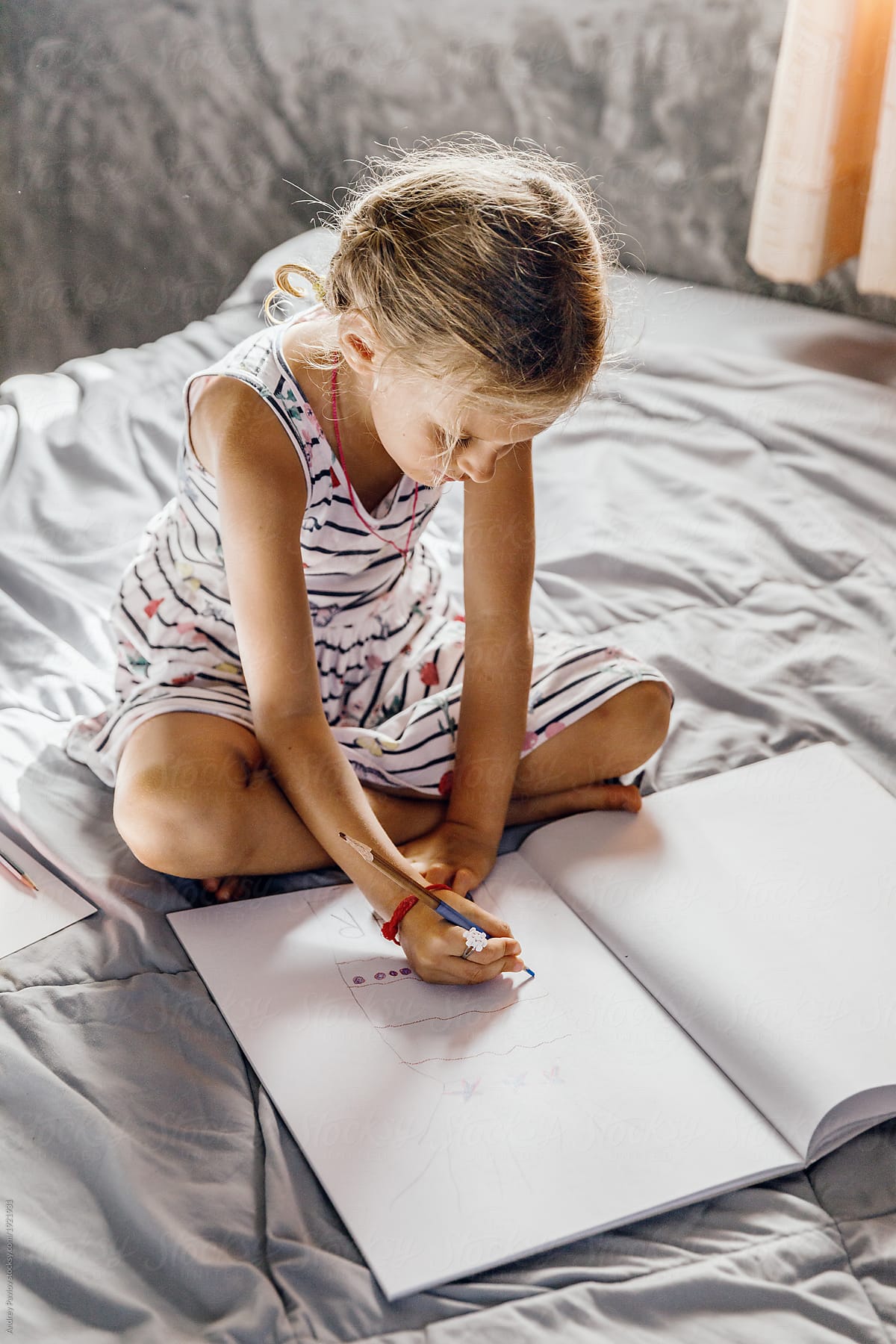 Little girl sitting on the bed and drawing