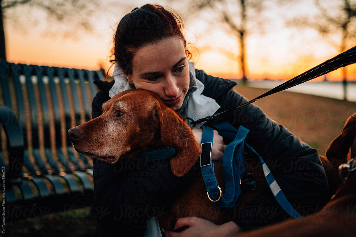A woman hugs a dog in the park