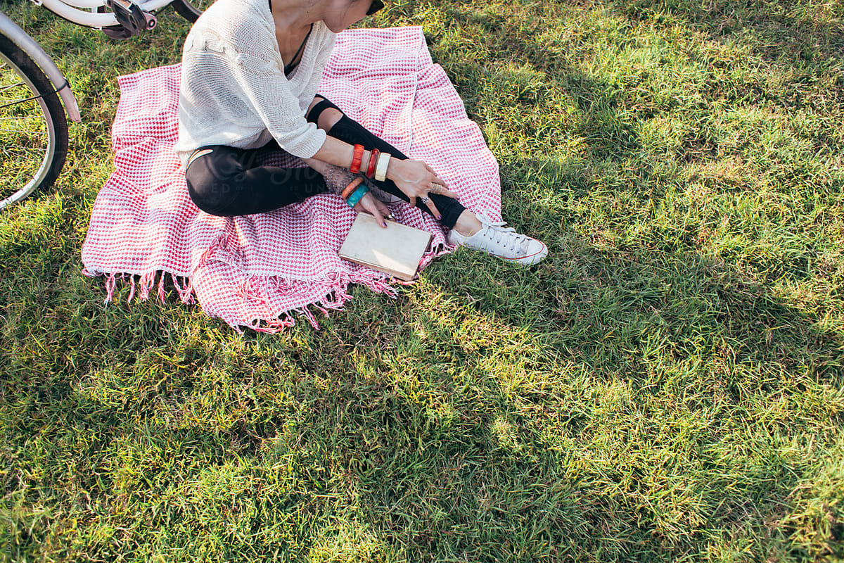 Spring time - woman sitting on a picnic rug and reading a book