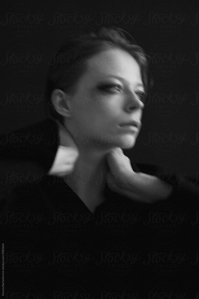 blurry black and white art portrait of a girl with a strong gaze with hands near her head