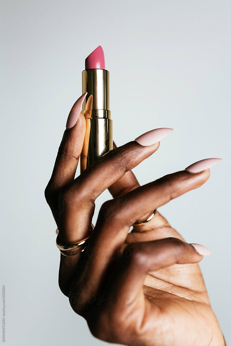 Crop ethnic model demonstrating lipstick