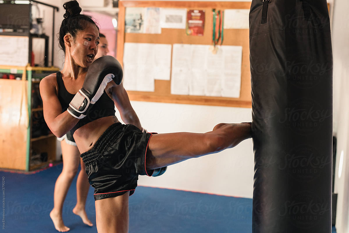 Thai Female Muay Thai Athlete Kicking On The Sand Bag