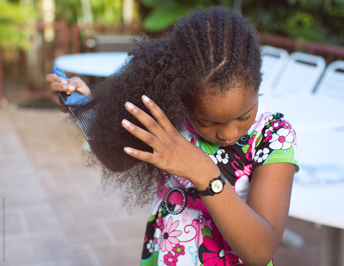 Young girl combing her curly kinky hair.