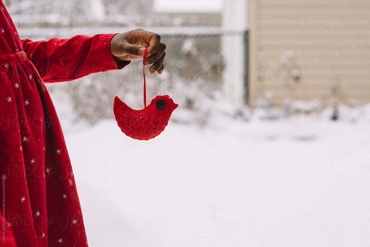 African American girl holding a handmade felt bird Christmas decoration in the snow