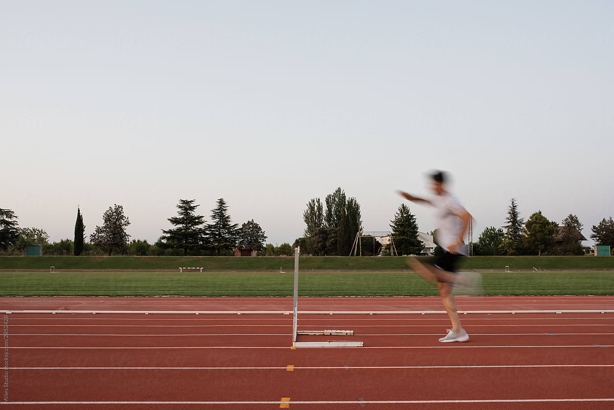 Blurred sportsman hurdling on track