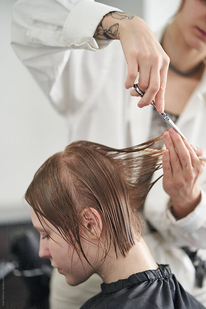 Crop hairstylist cutting wet hair of client in salon