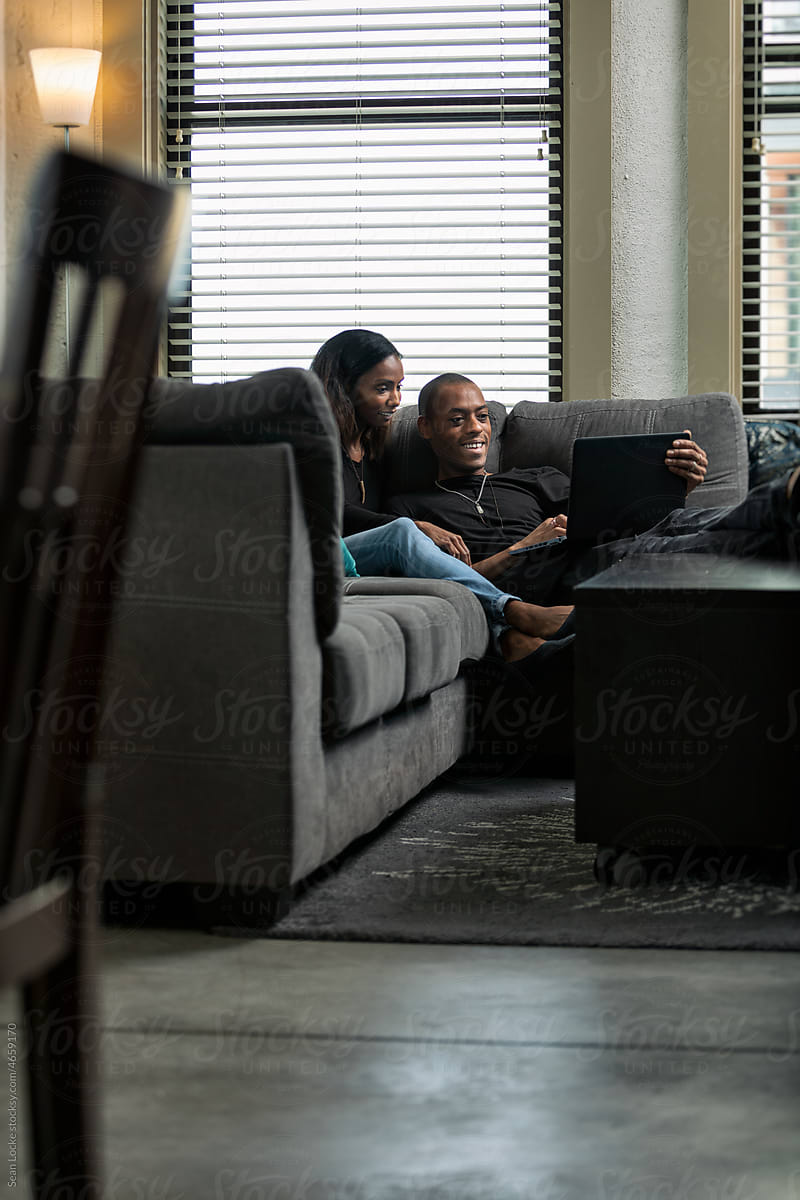 Loft: Couple Sits On Couch Looking At Laptop