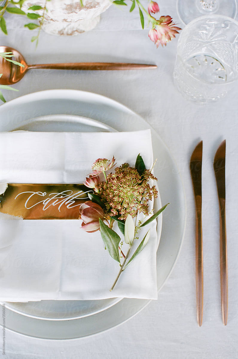 From above an elegant wedding reception tabletop with overgrown greenery, soft copper accents