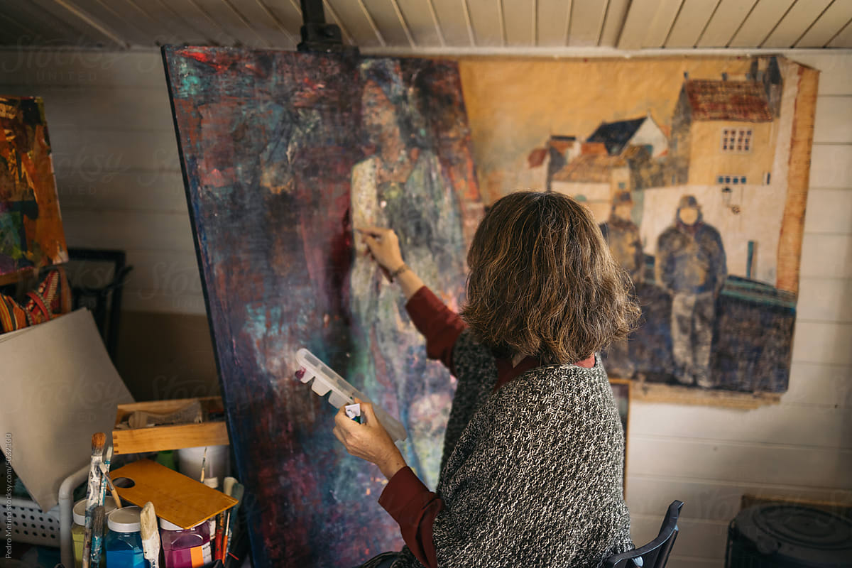 Mature woman artist painting an abstract picture on a canvas