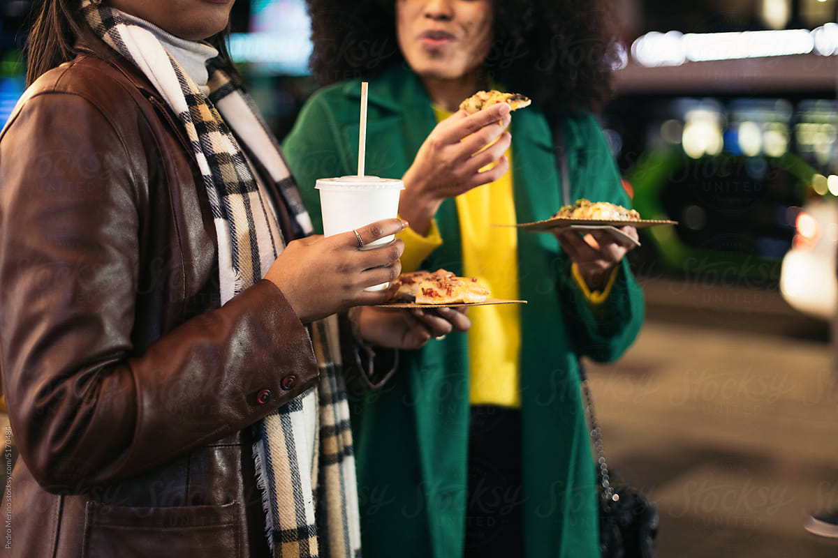 Close up of women eating fast food on the street at night
