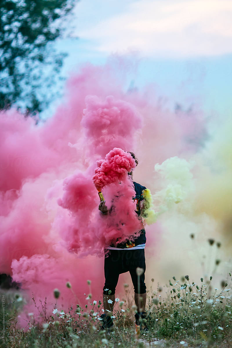 faceless,fashionable hipster man holding colorful smoke bombs in  nature