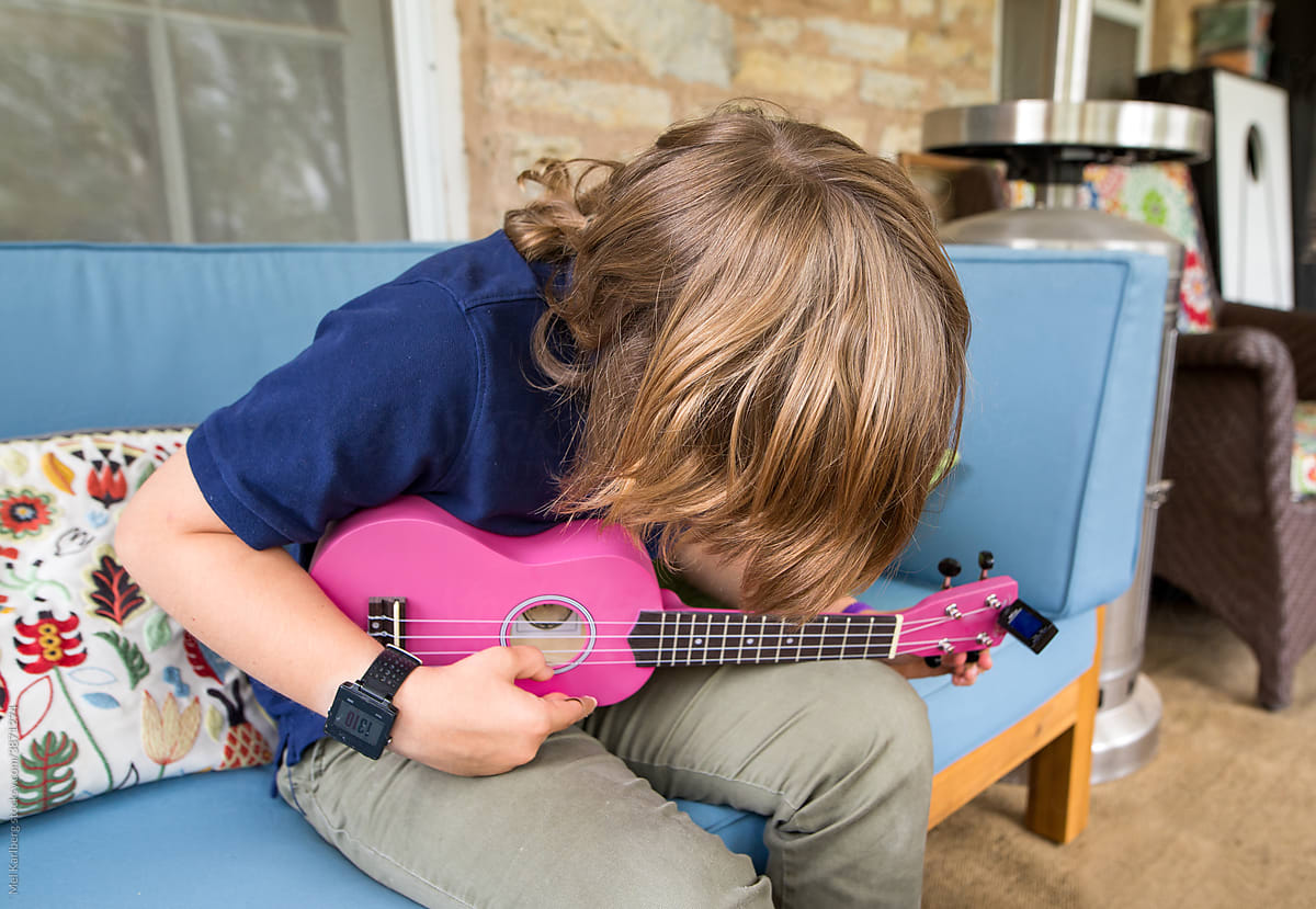 Long haired boy tuning a ukulele