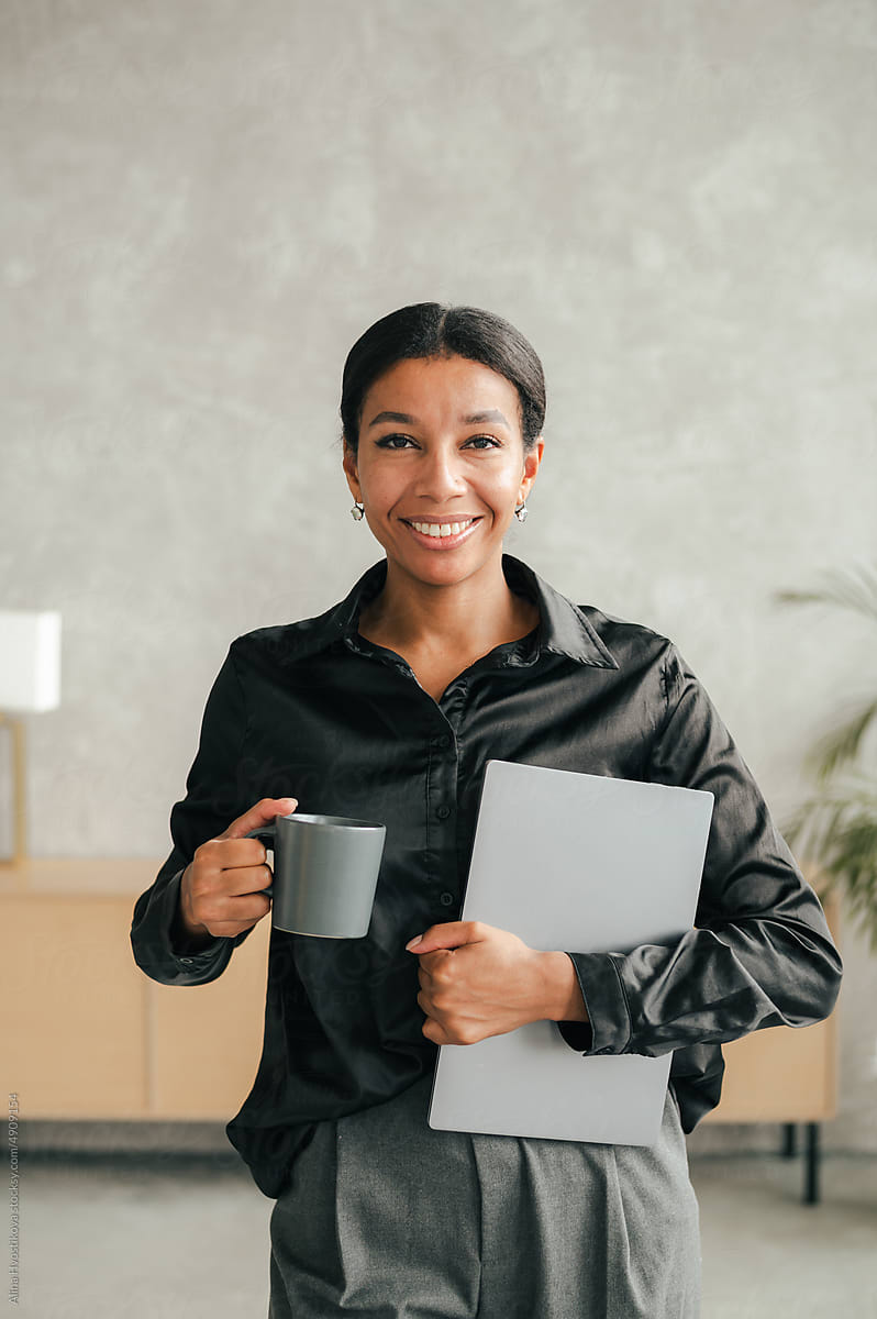 Cheerful woman with laptop and cup of coffee
