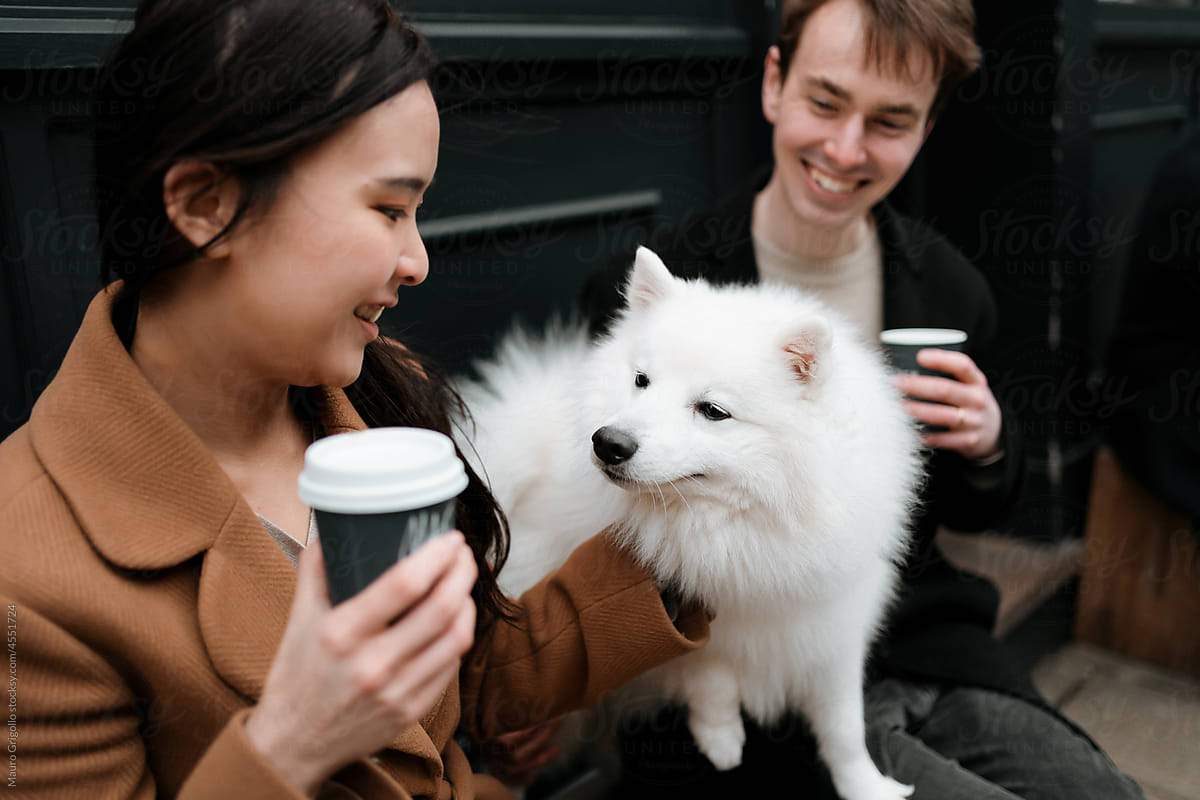 A couple drinks a coffee and has fun with their dog