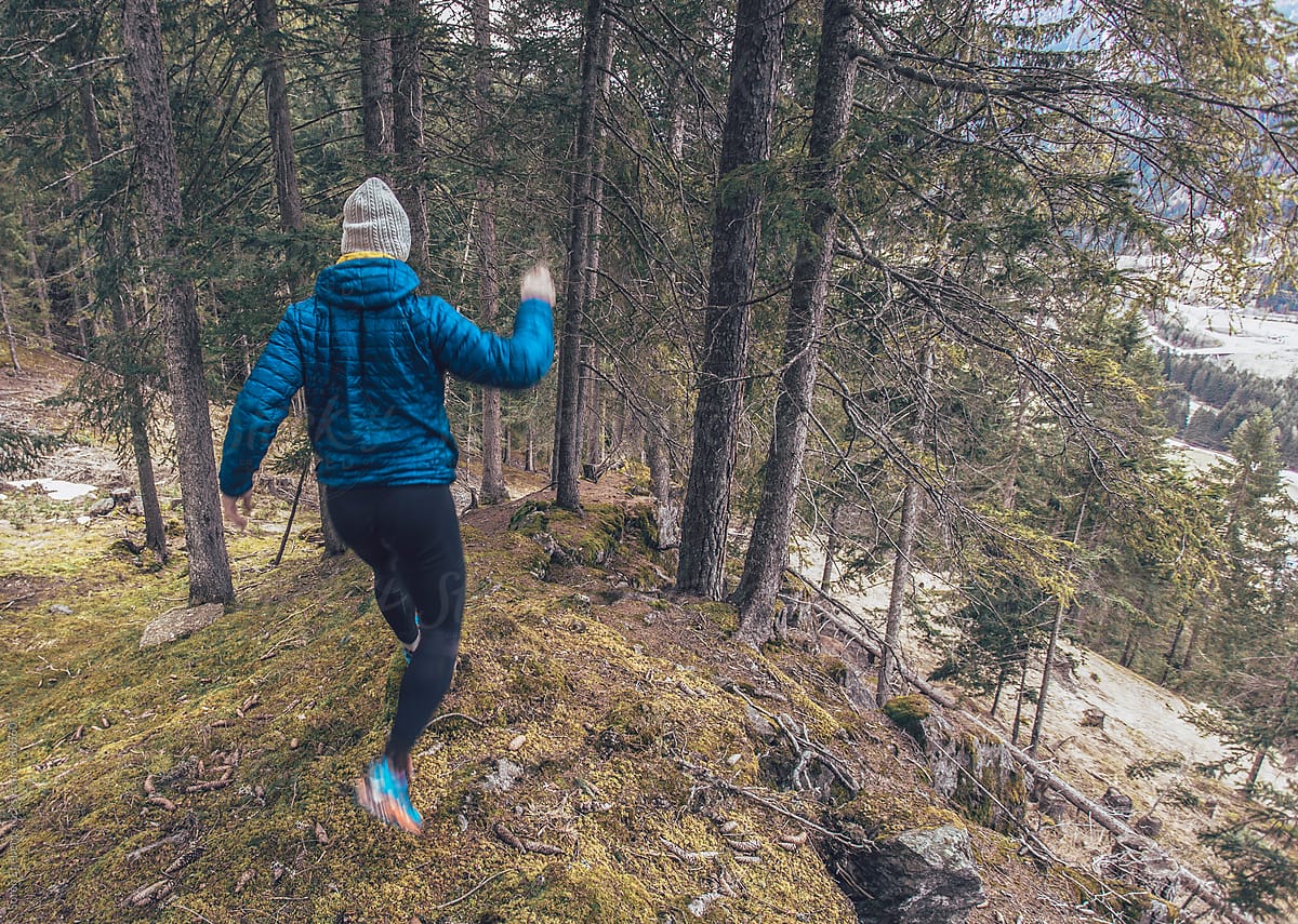 Runner jumping and running down forest mountains trail in spring