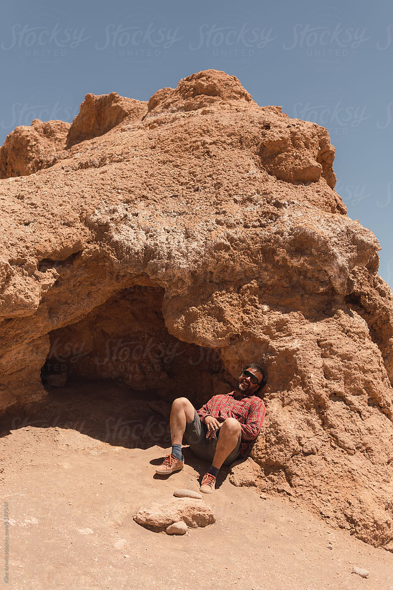 Man sitting under a rock
