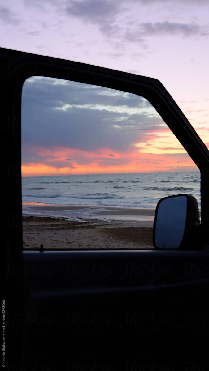 Sunrise in car doors on beach near fireplace on the  sea.