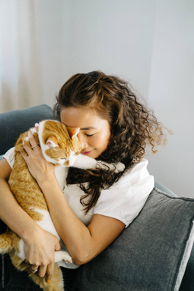 Asian female hugging cat on couch