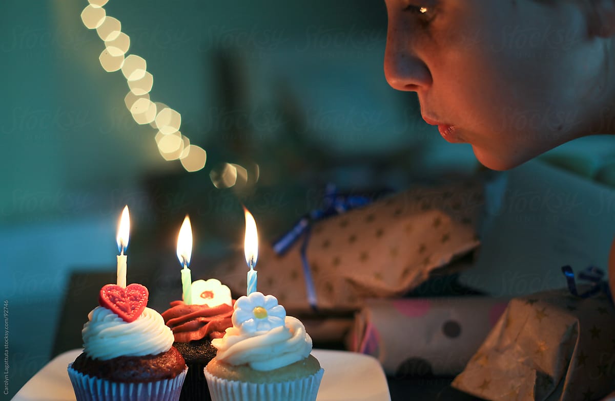 Girl Blowing Out Candles On Three Cupcakes By Stocksy Contributor Carolyn Lagattuta Stocksy