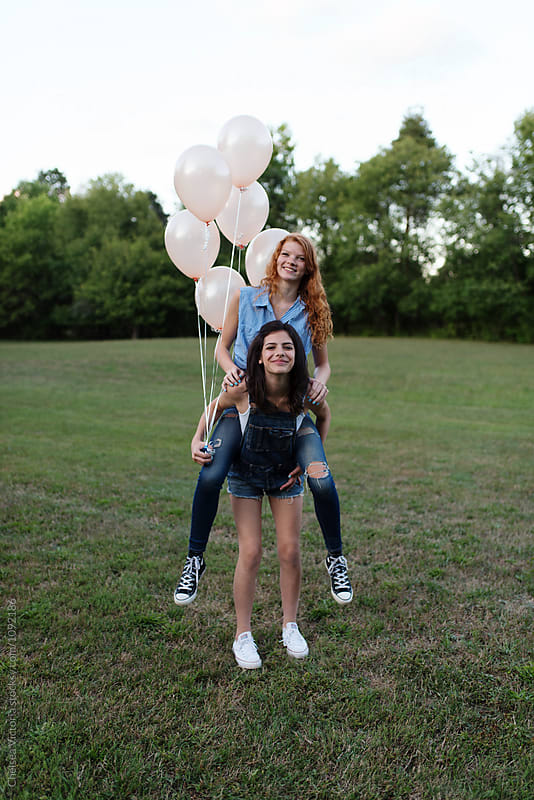 Two best friends outside playing with balloons