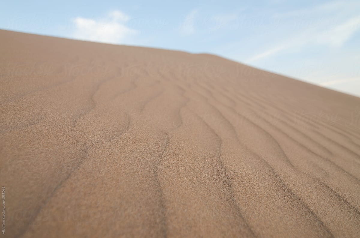 Bottom-up view of sand dune against blue sky