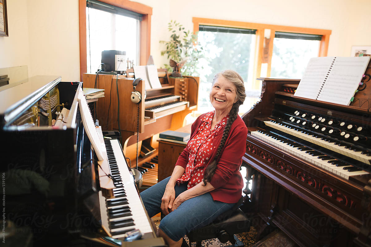 Happy mature woman playing piano and organ in home studio