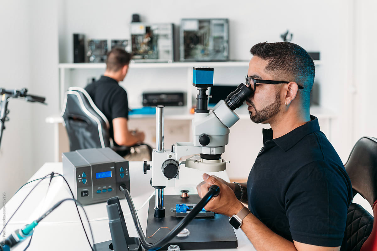 Technical specialist using microscope in workshop