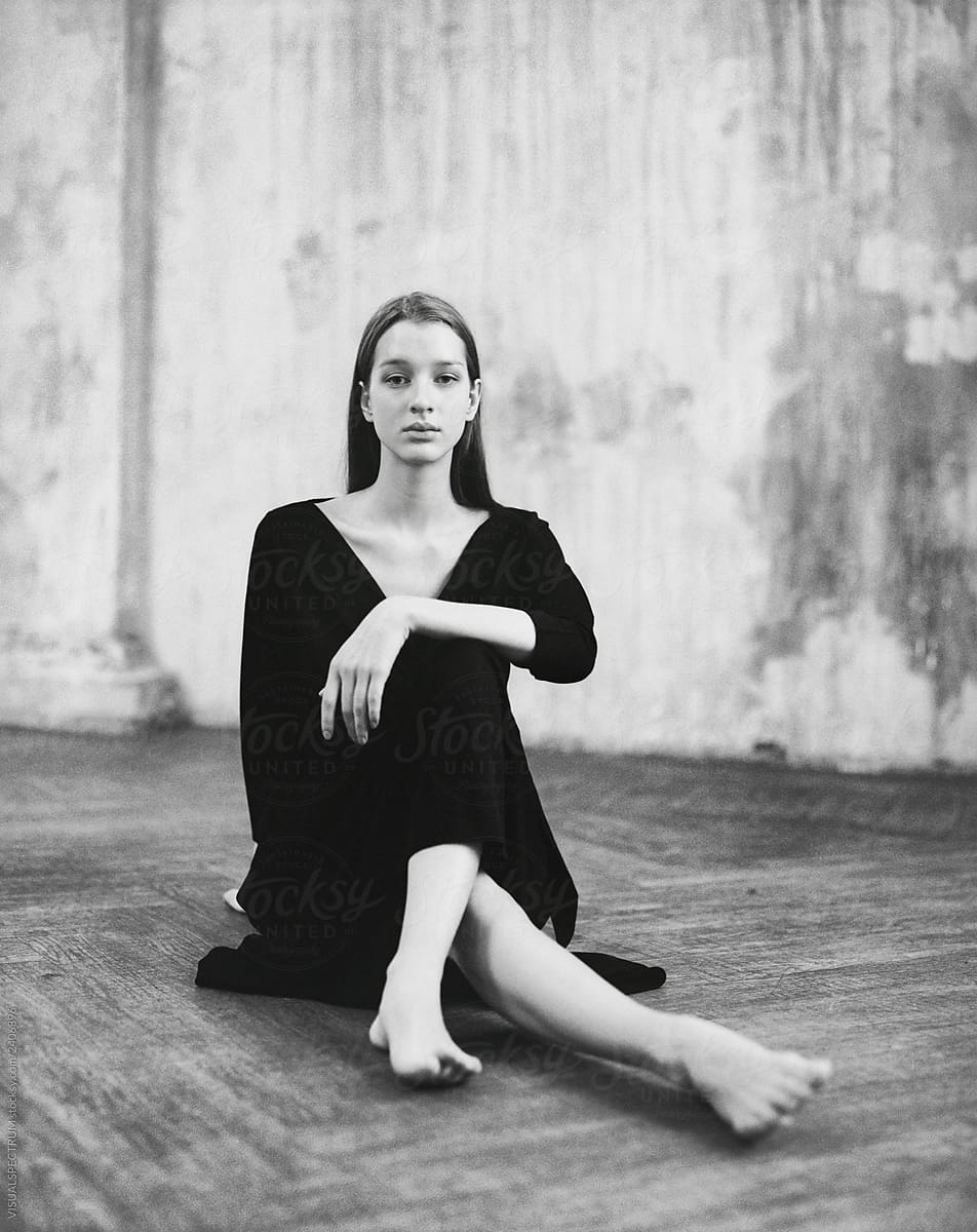Black and White Portrait of Young Graceful Woman Sitting on Wooden Floor