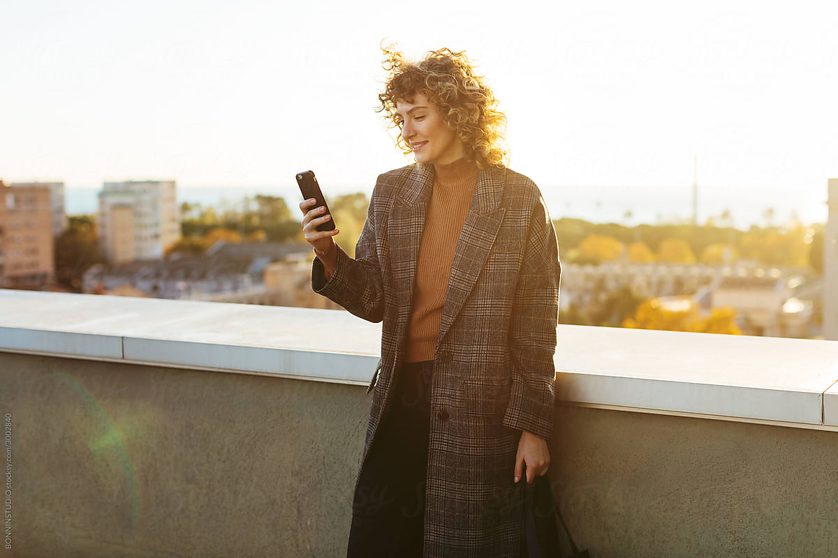 Trendy lady using smartphone on rooftop