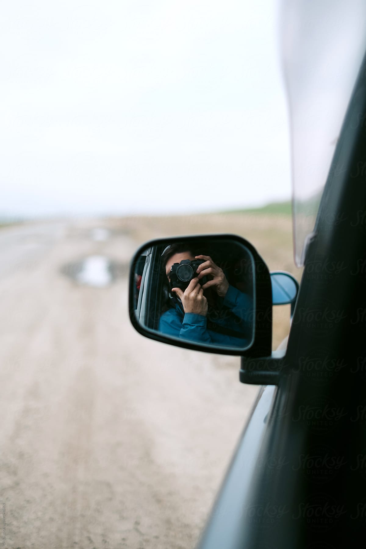 Young man taking photo in the mirror of a car