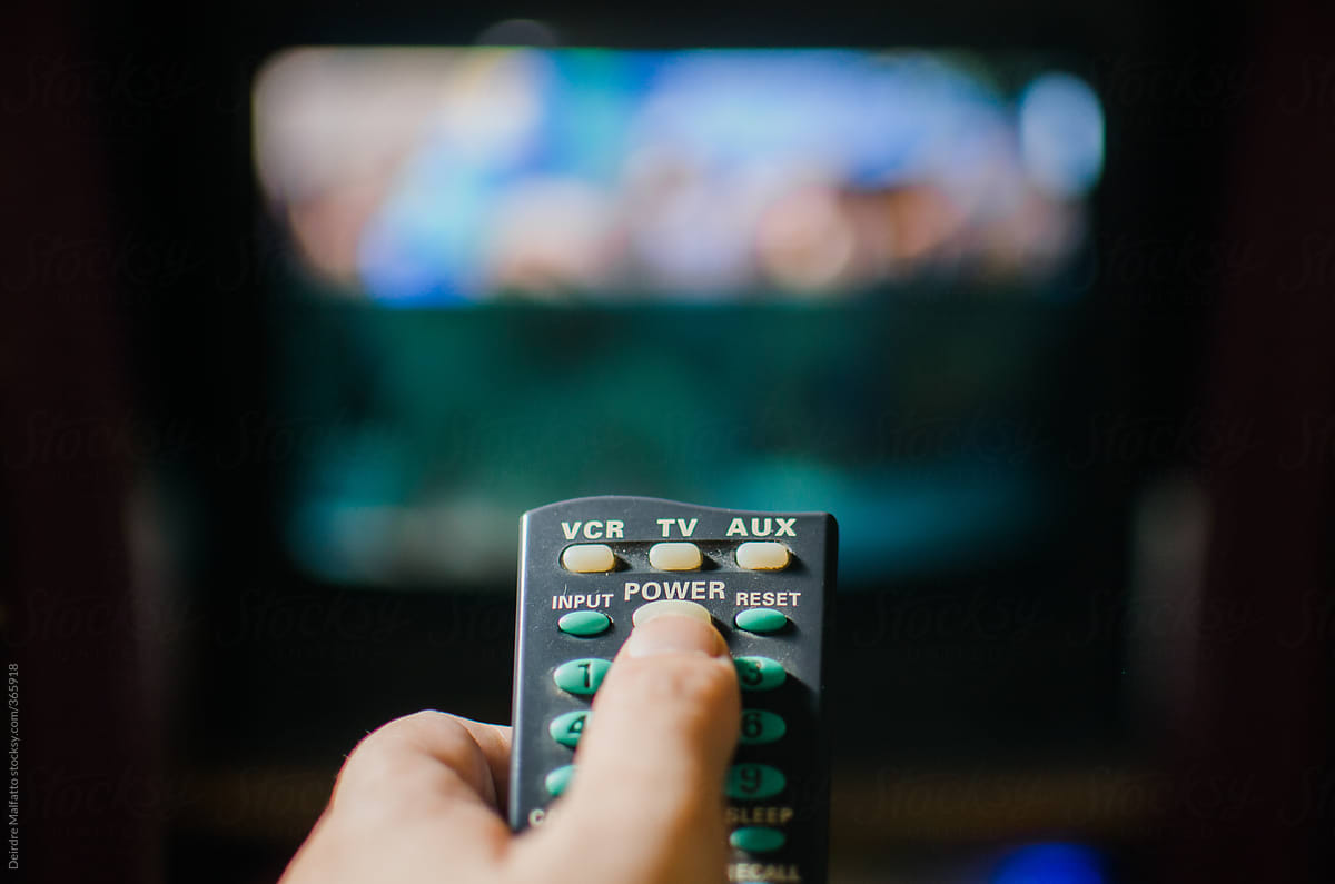 hand using old remote to control television