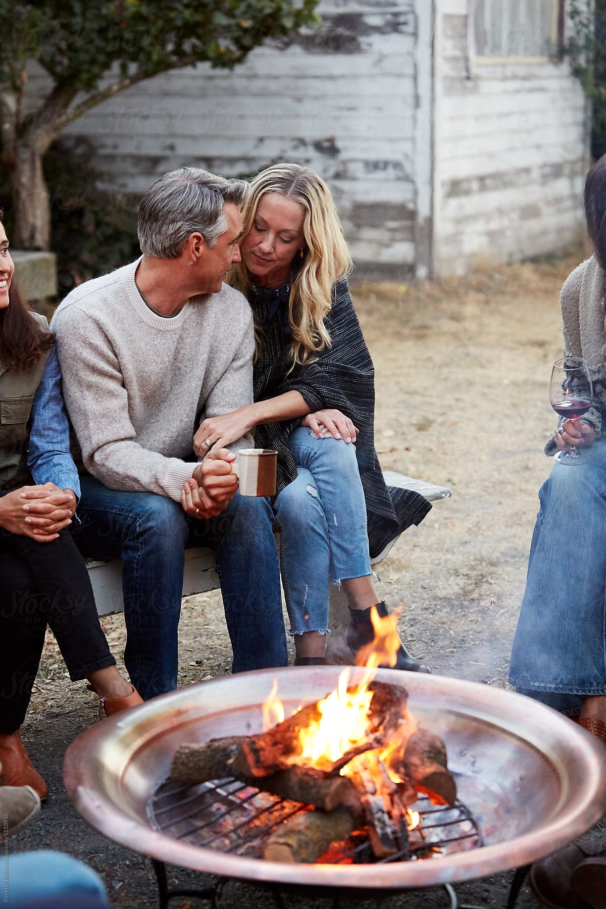 Group of friends and family relaxing around a fire pit at a farm