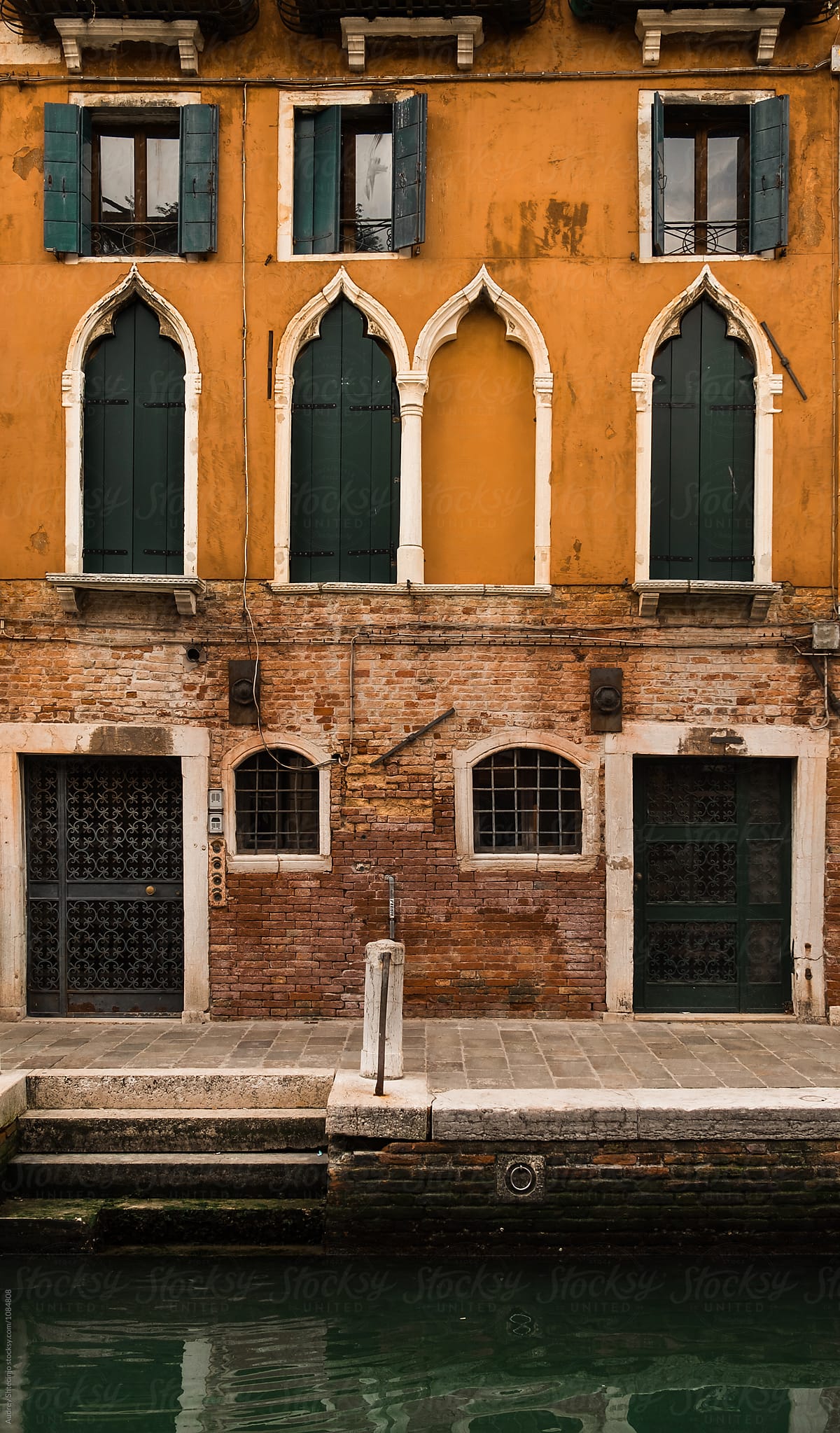 Building with yellow rustic facade with water canal in front of it. Venice/Italy