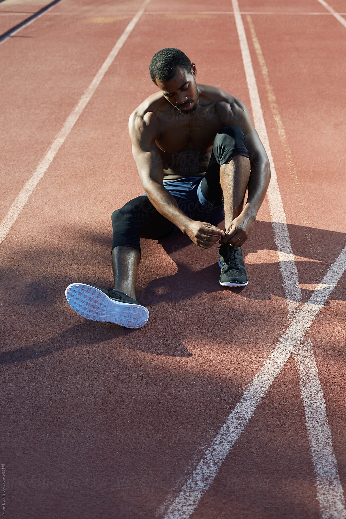 Black athlete tying his shoes  in the track and field