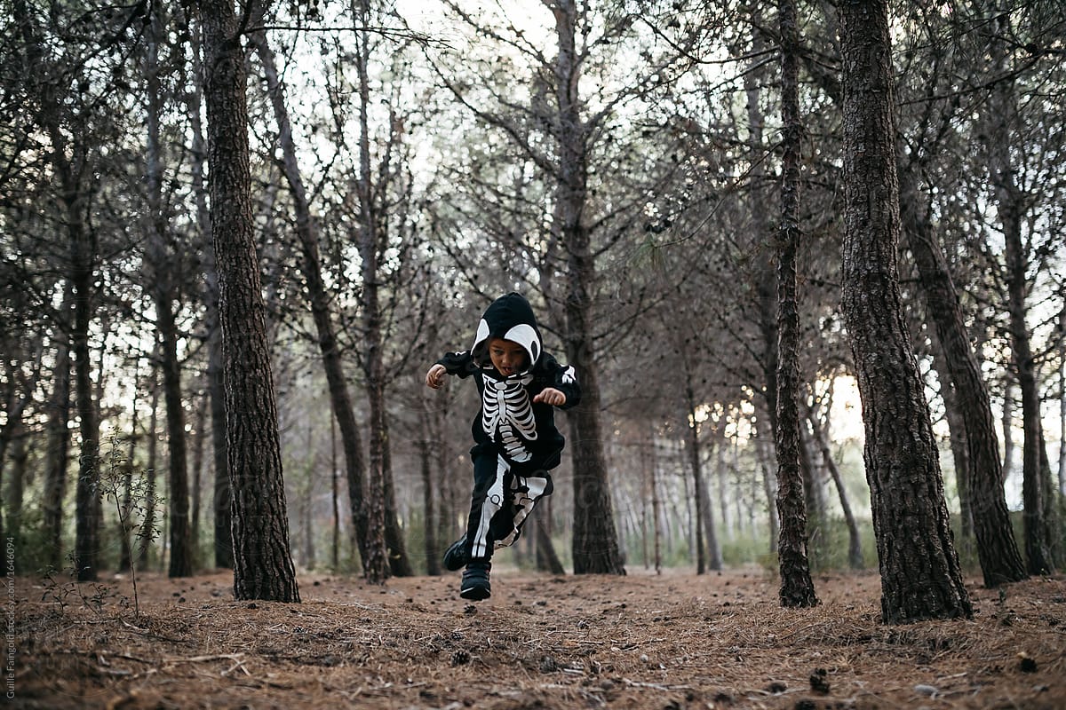 Halloween boy running in forest.