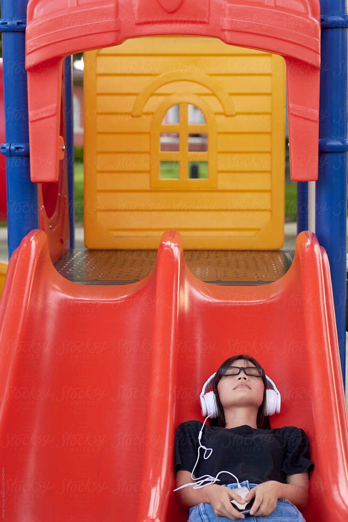 Teenager Listening To Music On A Kids Slide