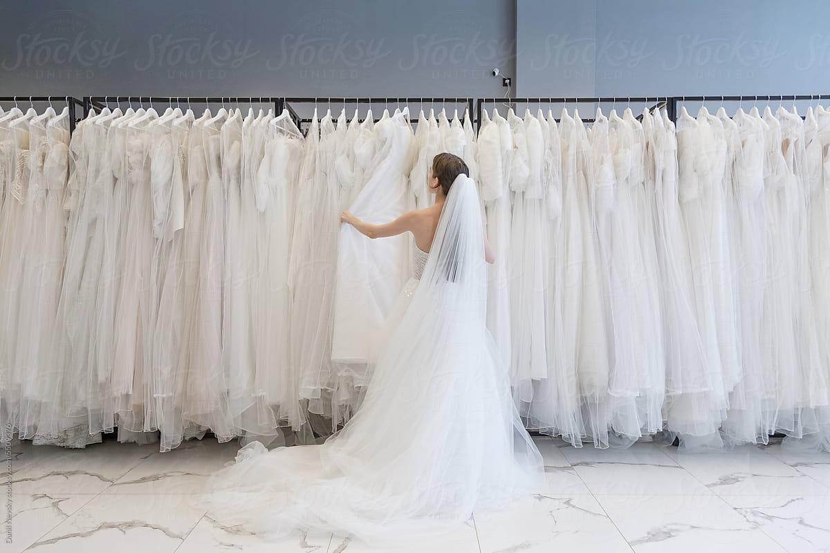 Woman choosing wedding dress from wardrobe at shop