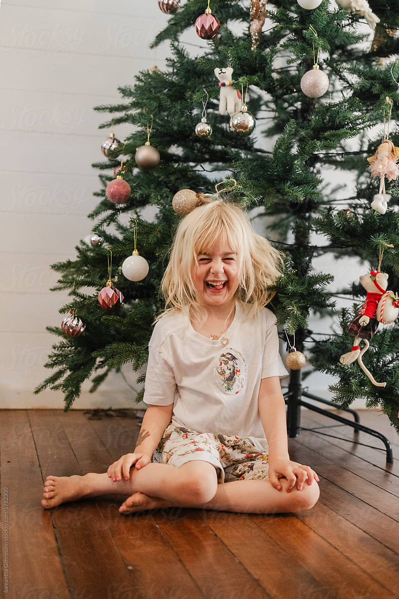 little girl in summery Christmas outfit under a Christmas tree