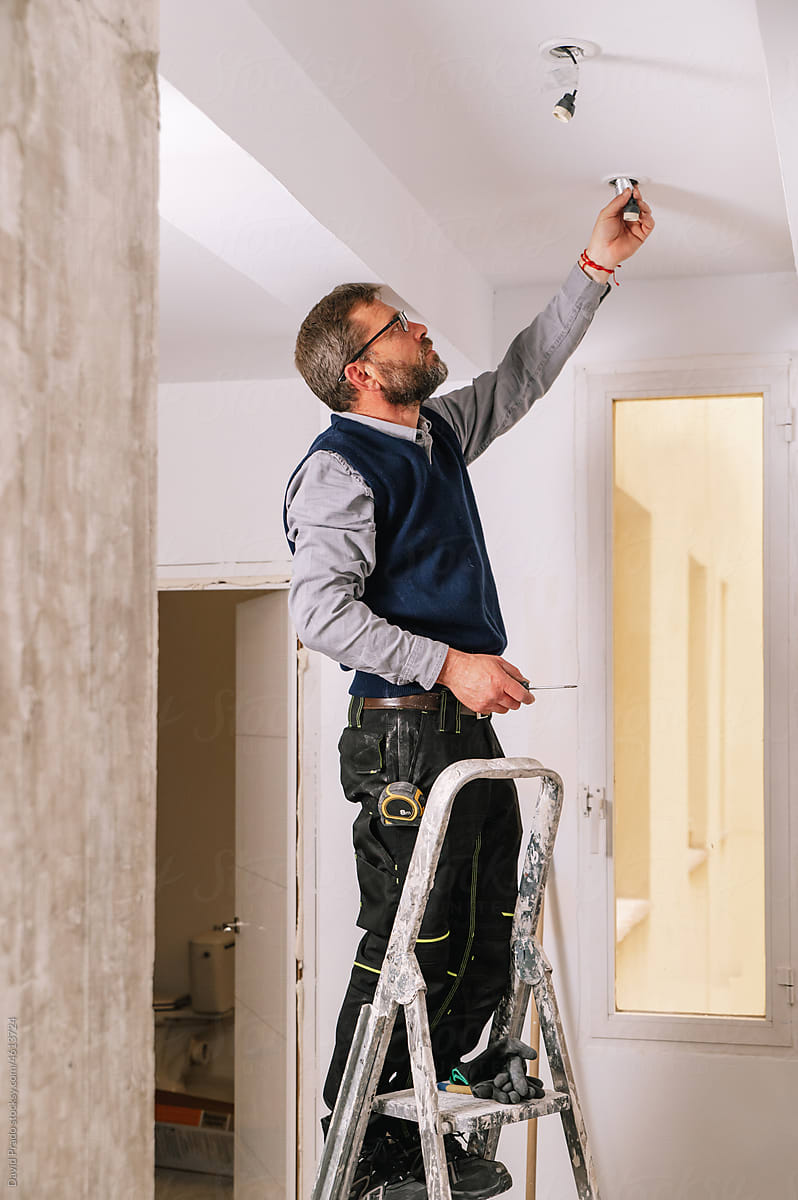 Male electrician installing ceiling illumination