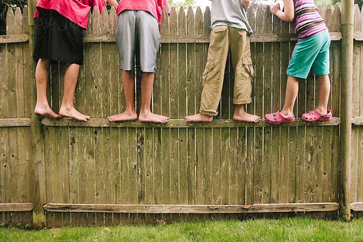 Children barefoot in summer while looking over fence