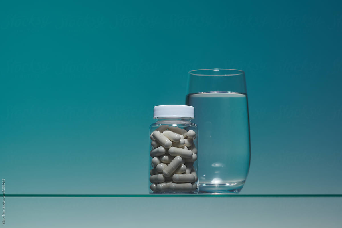 Pills capsules in bottles transparent with water glass