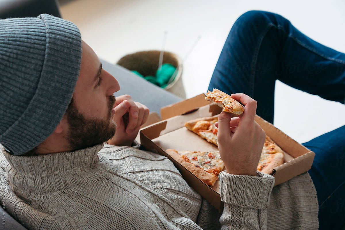 Modern male eats pizza indoor.