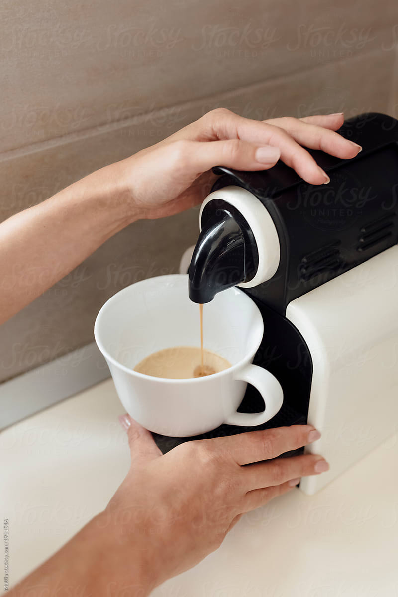 Adult Blonde Woman Preparing Coffee with a Machine At Home