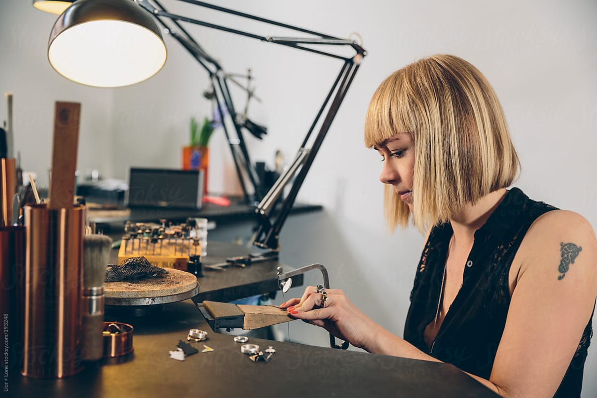 Young attractive jewelry designer working on a piece in her workshop