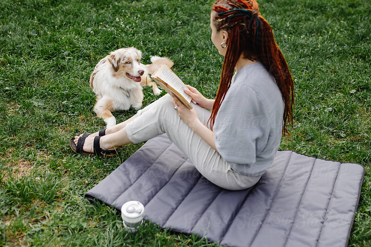 Woman with dog enjoying book outdoor