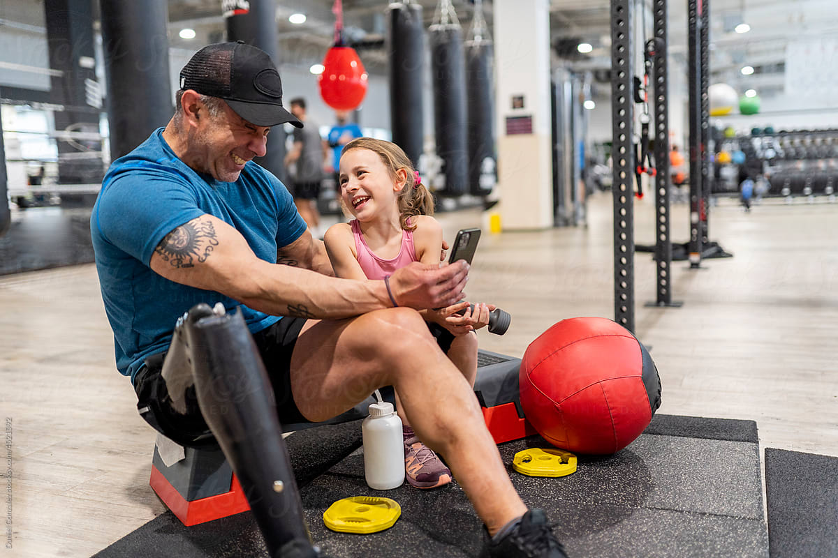 A disable man and his daughter smile together at the gym