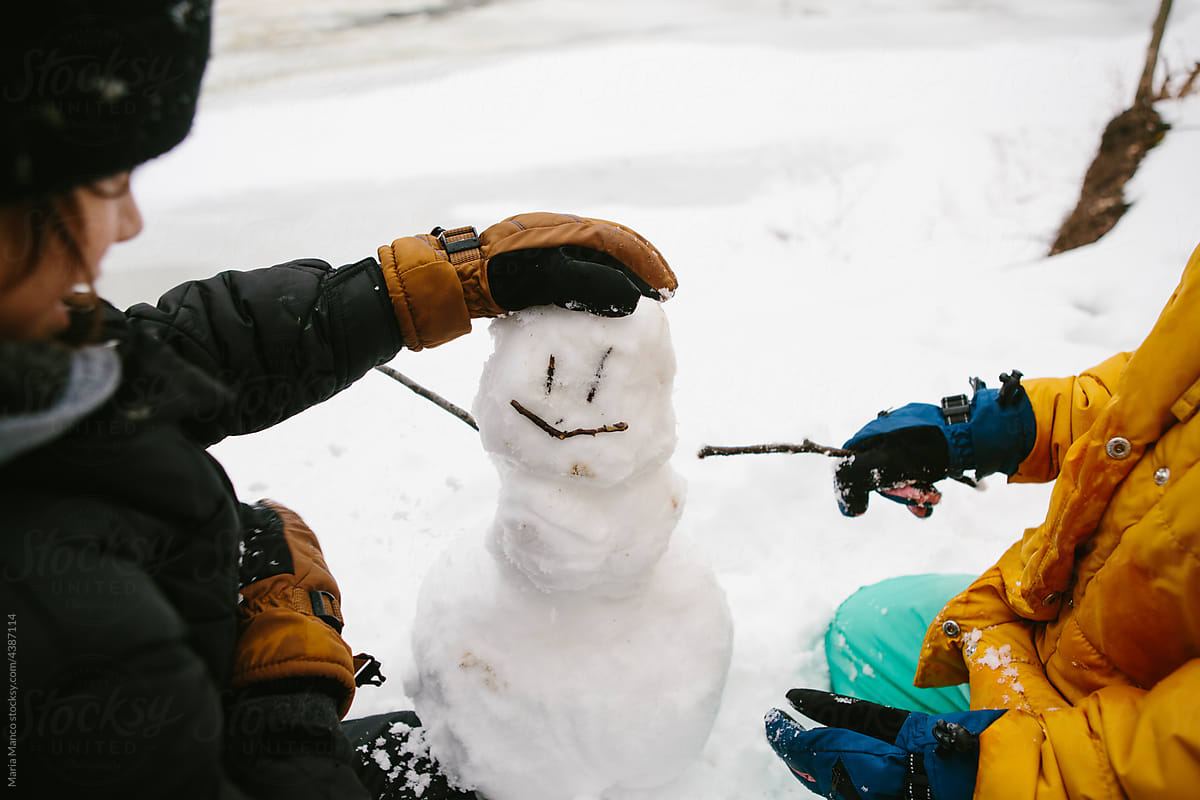 kids make a little snowman in the forest in winter