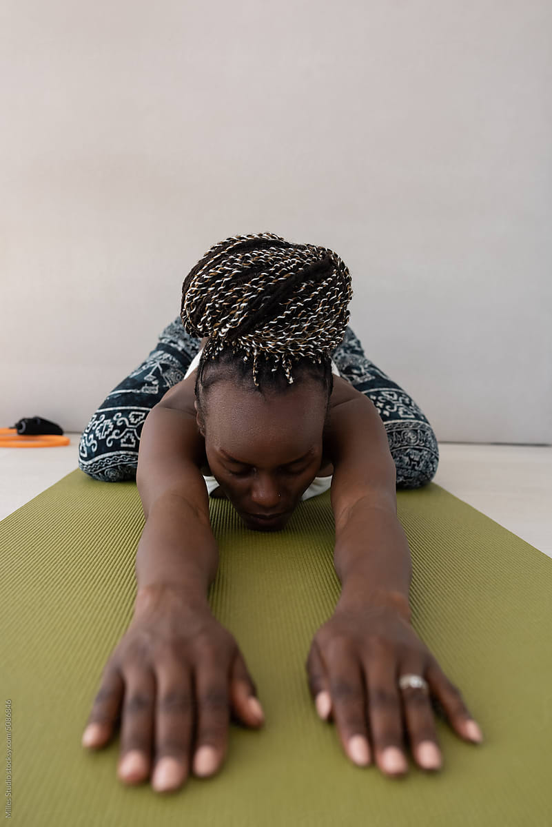 Black woman practicing Balasana on yoga mat