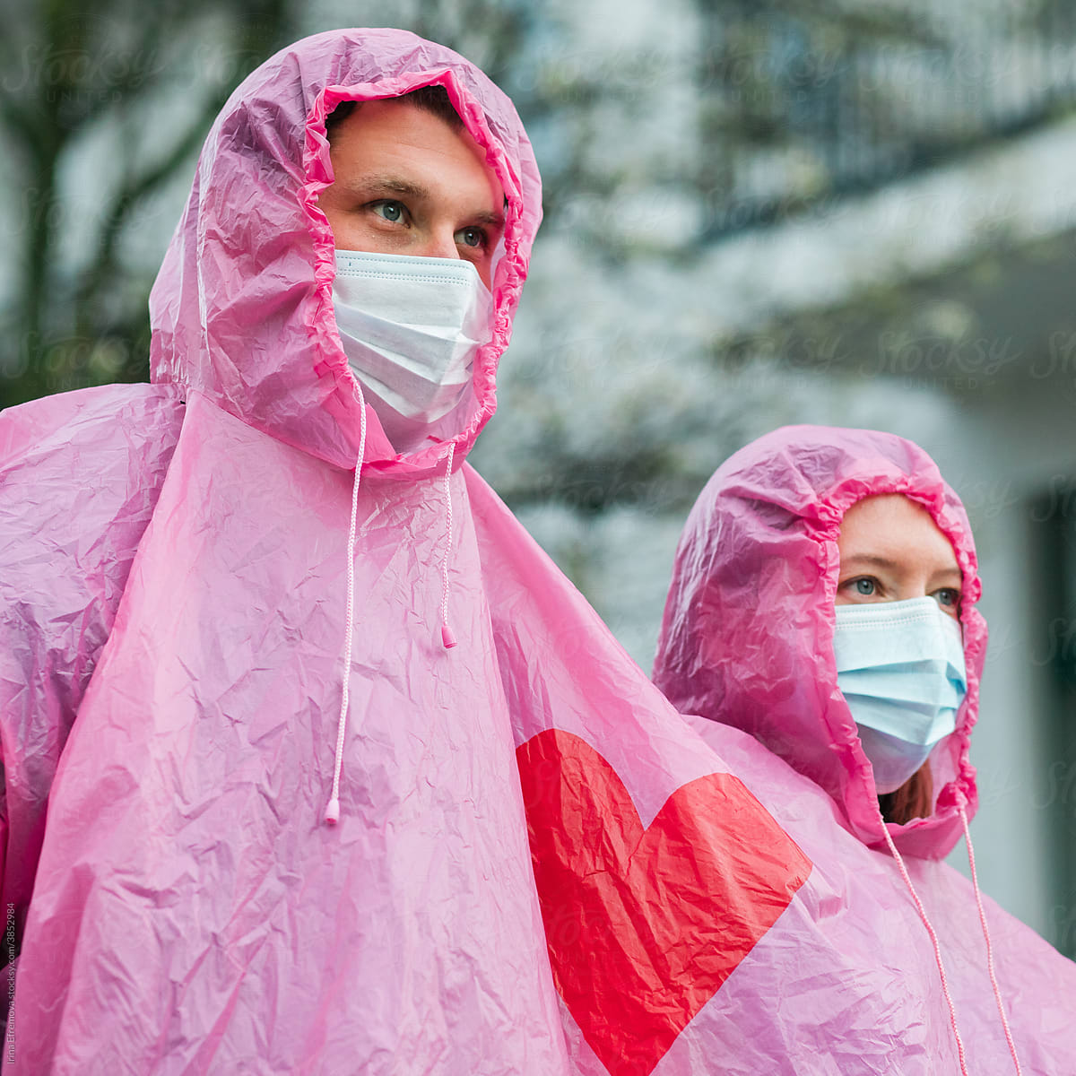 Man and woman wearing masks outside on the rain