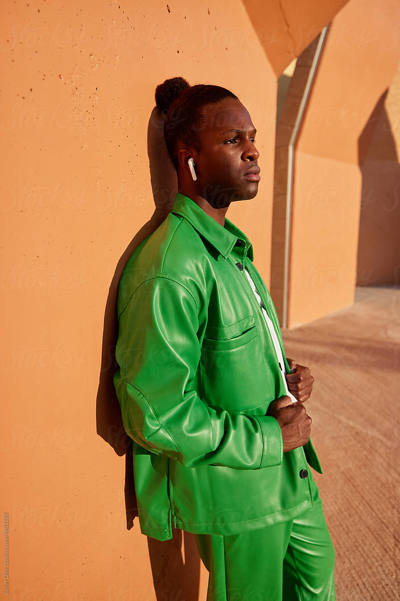 Serious black man in green suit leaning on wall